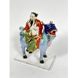 A Japanese porcelain figure of a dignitary with fan, seated on a deer, mounted on plastic base, (7cm