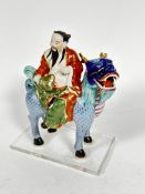 A Japanese porcelain figure of a dignitary with fan, seated on a deer, mounted on plastic base, (7cm