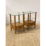 Ercol, A pair of blonde elm bedside tables, each with glass top over adjustable glass shelf and