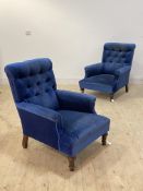 A pair of deep seated Edwardian easy chairs, upholstered in buttoned velvet, raised on turned