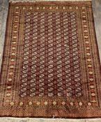 An Afghan bokhara hand knotted wool rug, the brown field with gul motif and bordered 317cm x 224cm