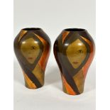 A pair of lacquered Art Deco style ovoid vases with gilded and lacquered stylised face decoration,