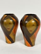 A pair of lacquered Art Deco style ovoid vases with gilded and lacquered stylised face decoration,