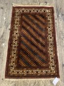 A Persian style rug, the red ground with geometric design within an ivory border 79cm x 143cm