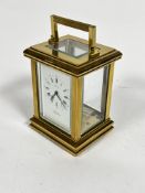 A Postilion quartz four glass clock with handle to top and enamel dial with roman numerals (h.14cm x