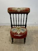 A Victorian ebonised prie dieu chair, upholstered crest rail over spindle back, moving on brass