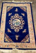 A Chinese washed wool pile rug, the deep blue field with dragon medallion and floral spandrels