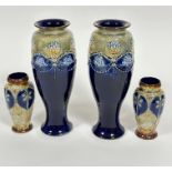 A pair of Doulton Lambeth baluster vases with applied and moulded decoration of vases of flowers and