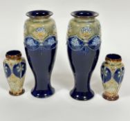 A pair of Doulton Lambeth baluster vases with applied and moulded decoration of vases of flowers and