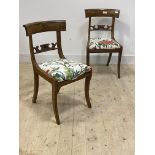 A pair of Regency mahogany side chairs, scrolled rail back over drop in seat pads, raised on sabre