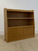 A vintage hardwood bookcase, with two open shelves over two sliding doors, H98cm, W103cm, D29cm