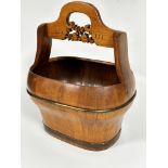A Chinese elm water bucket of oval form with arched handle to top and carved stylised fruit and leaf