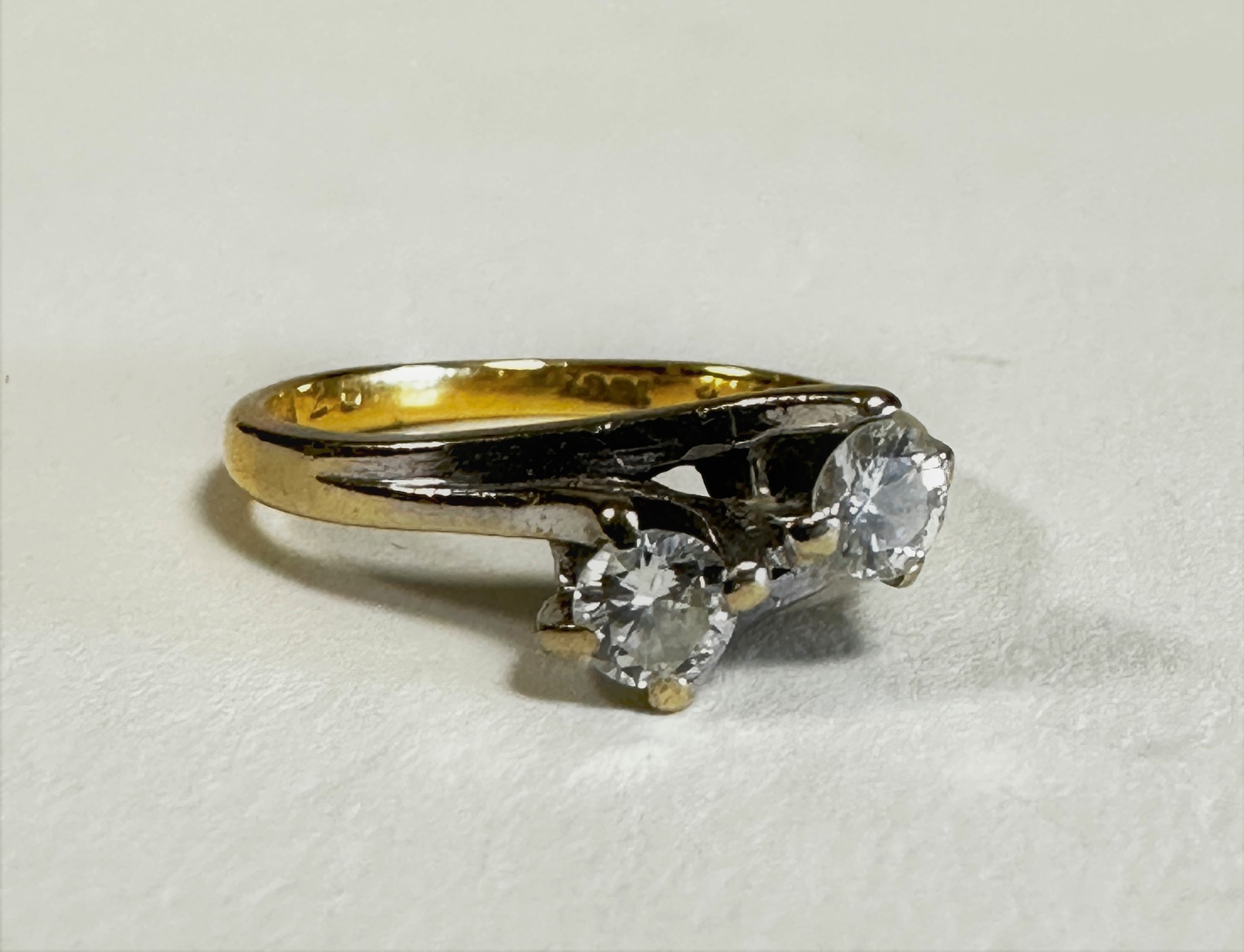 An 18ct gold yellow and white metal two stone diamond crossover ring, mounted in scrolling claw