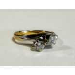 An 18ct gold yellow and white metal two stone diamond crossover ring, mounted in scrolling claw