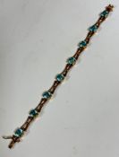 A 9ct gold link articulated line bracelet with X shaped links, set eight blue zircons in claw