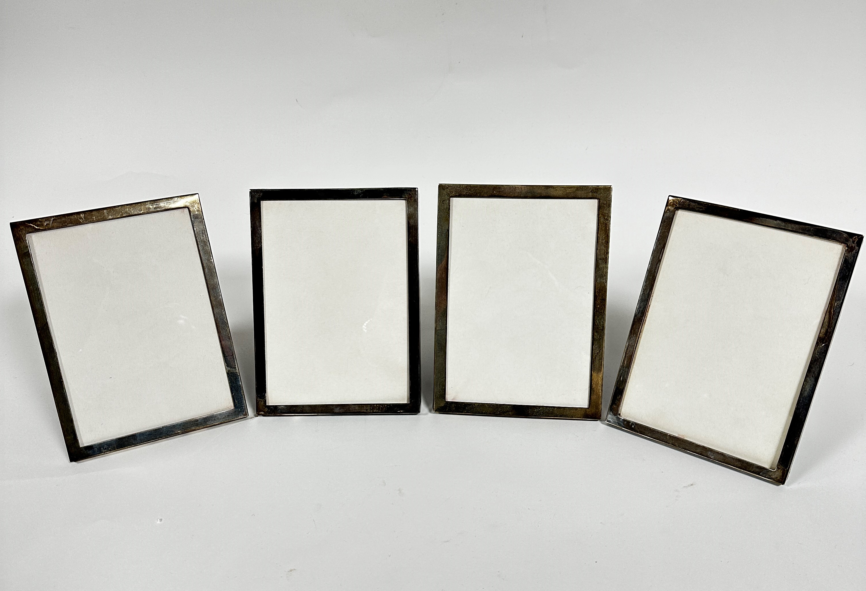 A set of four sterling silver rectangular photograph frames with plush mounted backs, (aperture 17.