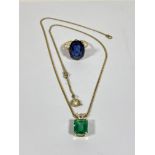 An oval cut blue stone ring, on 9ct band, together with a green stone pendant necklace on yellow