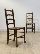 A pair of early 20th century oak ladder back chairs, with rush seats and turned supports, H100cm,