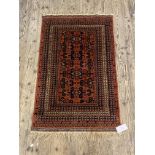 A Persian style rug, the red field with geometric repeating design and bordered 85cm x 145cm