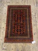 A Persian style rug, the red field with geometric repeating design and bordered 85cm x 145cm