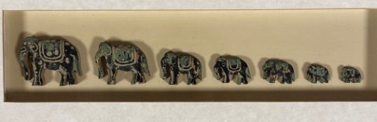 A box frame containing a Troop of Seven Graduated Elephants with gilded painted finish, glazed box