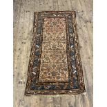 An antique Persian rug, hand knotted, the ivory field of stylised design, blue guarded border