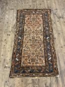 An antique Persian rug, hand knotted, the ivory field of stylised design, blue guarded border