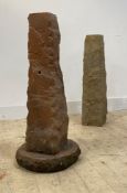 Two roughly hewn stone columns of square tapered form, one standing on a circular base, H90cm