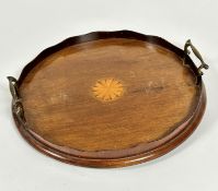 An Edwardian mahogany circular two handled tea tray with scalloped top with central satinwood inlaid