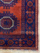 A hand knotted Bokhara runner rug, the red field with nine guls within a deep blue border 365cm x