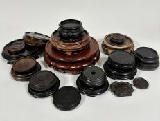 A collection of twenty various hardwood and ebonised stands and a ceramic stand, (largest d 22cm,