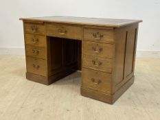 An early 20th century oak desk, the top with inset skivered writing surface over two slides, one