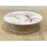 A contemporary circular low table, the floral patterned acrylic top over white metal supports,