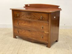 An early 20th century mahogany ledgeback chest fitted with three graduated drawers, raised on