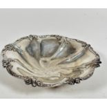 A Sheffield 1907 silver scalloped dish decorated with leaf and berry design, raised on four ball