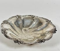 A Sheffield 1907 silver scalloped dish decorated with leaf and berry design, raised on four ball