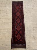 A Baluchi runner rug, the red field with lozenge motif, 255cm x 64cm