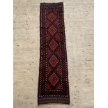 A Baluchi runner rug, the red field with lozenge motif, 255cm x 64cm