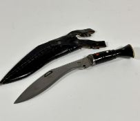 A tempered steel kukri style knife with leather scabbard and water buffalo horn handle with brass