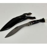 A tempered steel kukri style knife with leather scabbard and water buffalo horn handle with brass