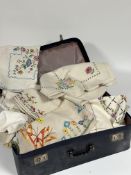 A blue leather suitcase, with satin lining containing a collection of various hand stitched linens