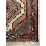A Persian Hamadan hand knotted runner rug, with pole medallion on red field enclosed by a border