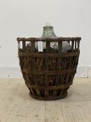 A large green glass demijohn, in a strap work cage, H60cm