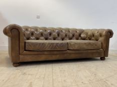 A quality Chesterfield sofa, upholstered in deep buttoned tan leather, raised on bun supports,