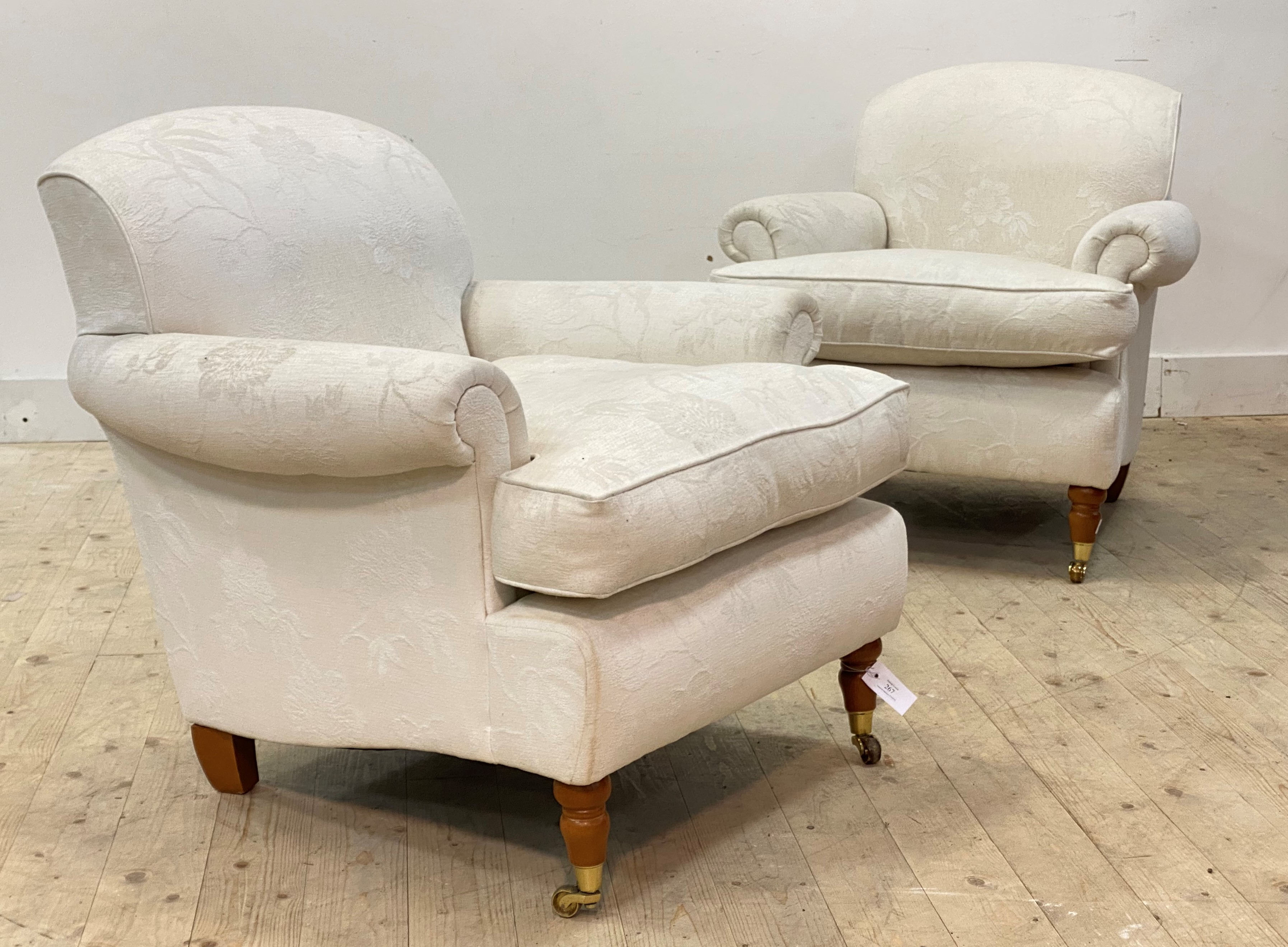 A pair of Victorian style easy chairs, upholstered in floral ivory damask fabric, raised on turned