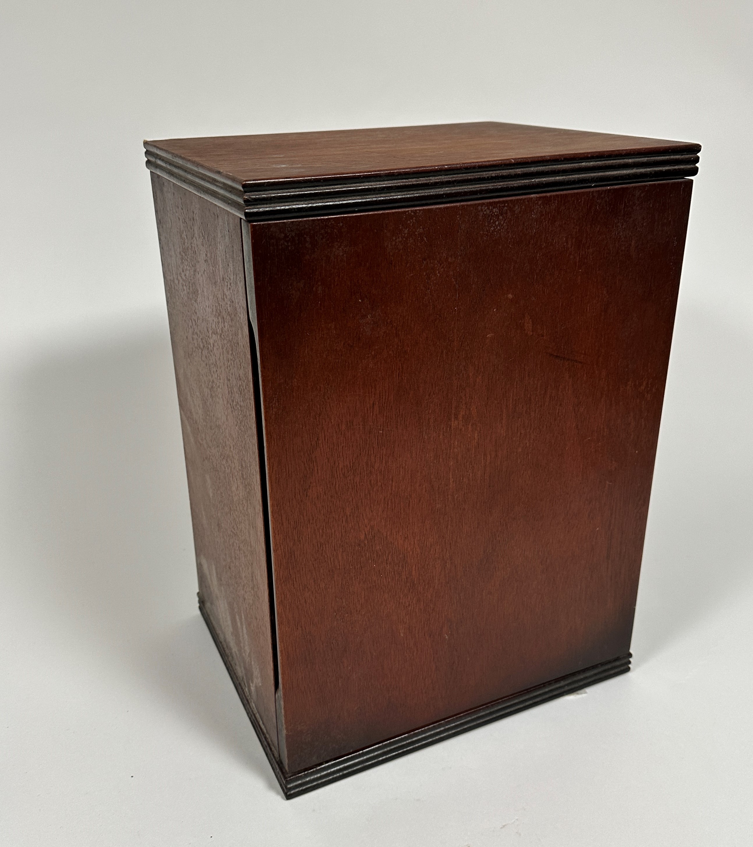 A mahogany cabinet, the rectangular top with reeded edge, above a hinged panel door enclosing a