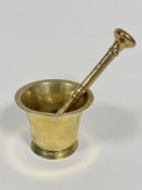 A brass mortar and bronze pestle, (mortar h 10cm x 12.5cm, pestle L 21cm)