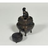 A Chinese bronze incense burner decorated with panels along the side showing a man reading,
