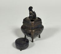 A Chinese bronze incense burner decorated with panels along the side showing a man reading,