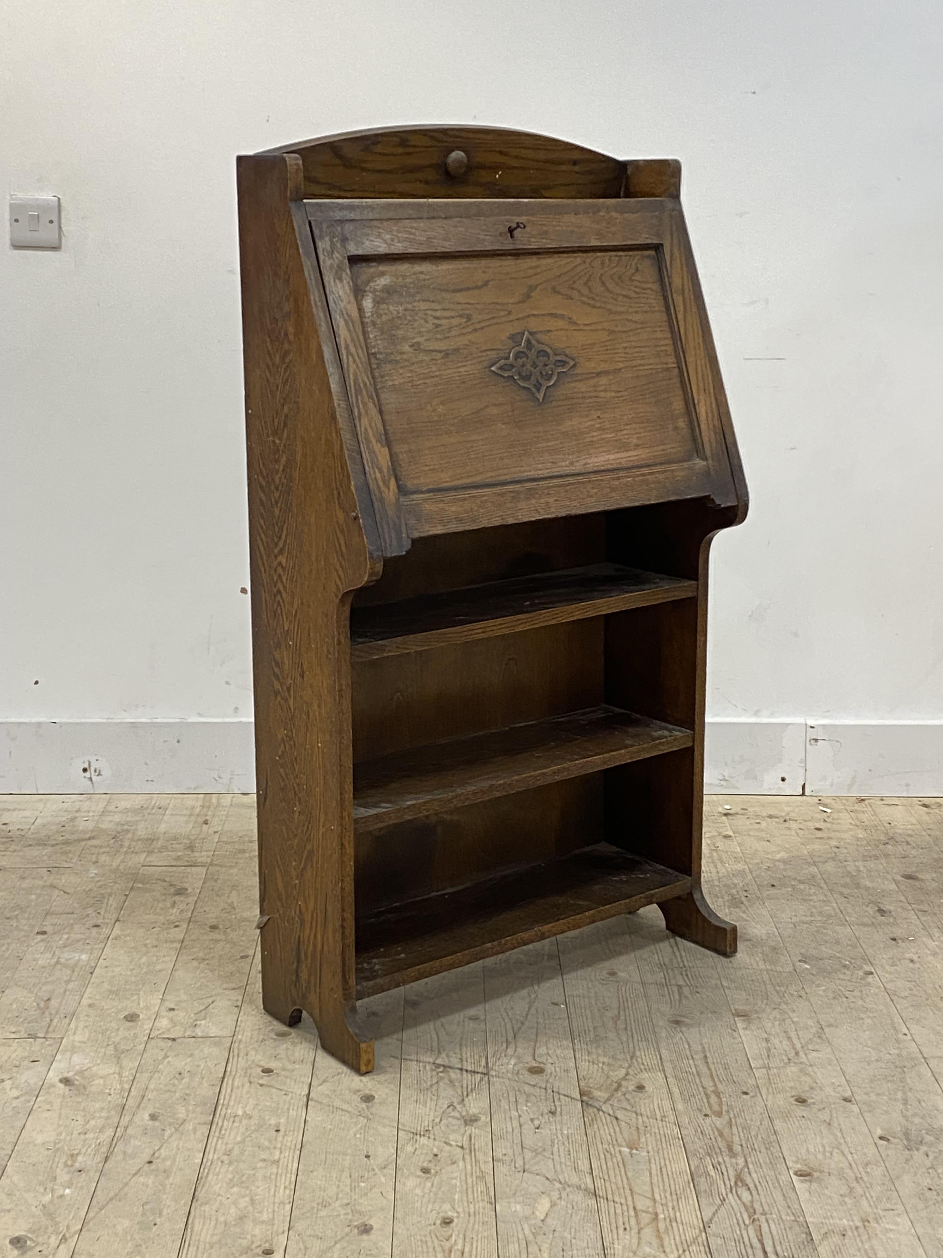 A 1930's/40s oak bureau, the fall front revealing fitted interior over two open shelves on panel end